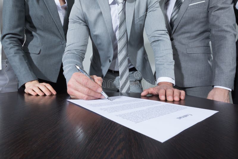contrato-de-assinatura-do-empresário-assinando-enquanto-sua-equipe-o-olha-279350934 (1)